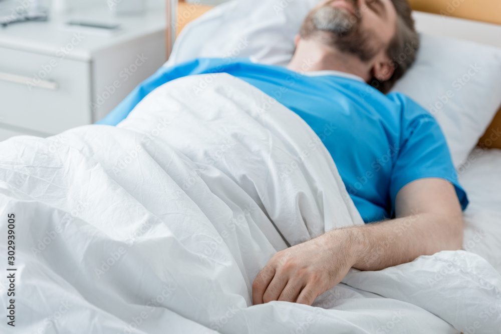 Obraz premium selective focus of patient in medical gown sleeping in hospital