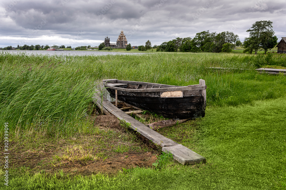 Russia, Republic of Karelia, Kizhi Island: Old traditional wooden boat at riverside of Lake Onega with Transfiguration Church on Kizhi Pogost, a historical site and Russian national open air museum.