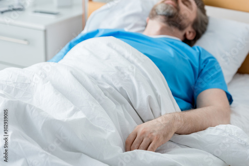 selective focus of patient in medical gown sleeping in hospital