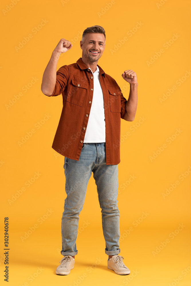 cheerful man standing with clenched fists on orange cheerful man standing with clenched fists on orange