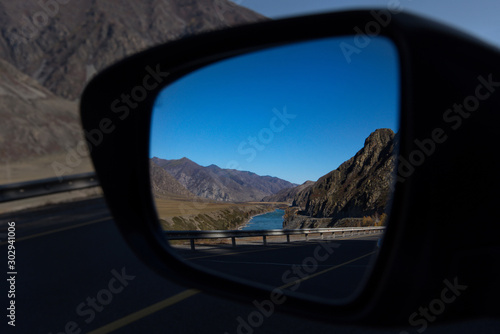 Russia. Mountain Altai. Reflection of the Chui tract in the side mirror of the car near the village of Maly Yaloman