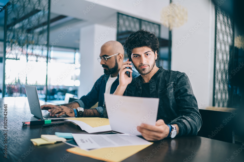 Obraz premium Handsome man having phone call working with colleague