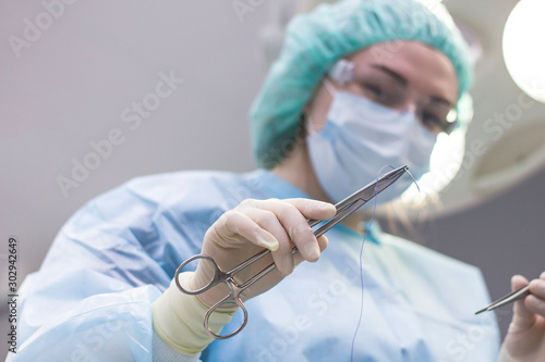 Surgeon resuscitator, close-up cuts the thread during surgery, suture the patient. The doctor in the operating room holds a metal tool closeup