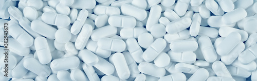 White pills spilled on blue wooden background photo