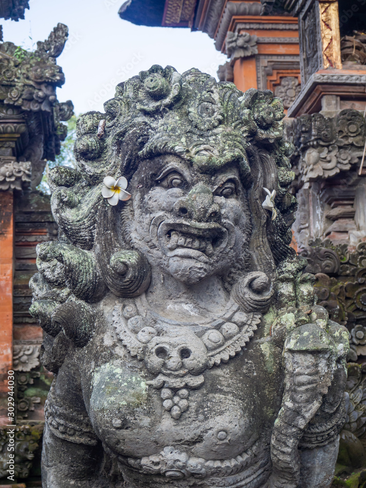 Temple with statues covered with moss on the island of Bali