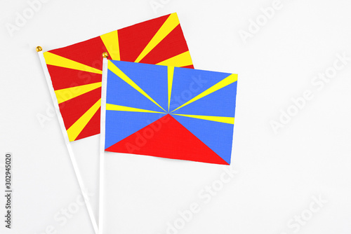 Reunion and Macedonia stick flags on white background. High quality fabric, miniature national flag. Peaceful global concept.White floor for copy space.