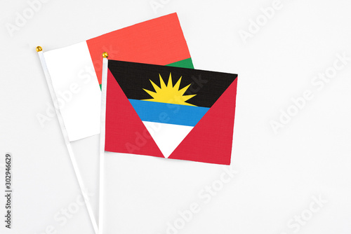 Antigua and Barbuda and Madagascar stick flags on white background. High quality fabric, miniature national flag. Peaceful global concept.White floor for copy space.