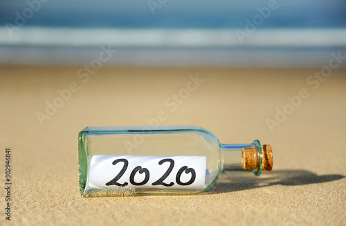 2020 Summer vacation concept. Message in a bottle on the sand of beach
