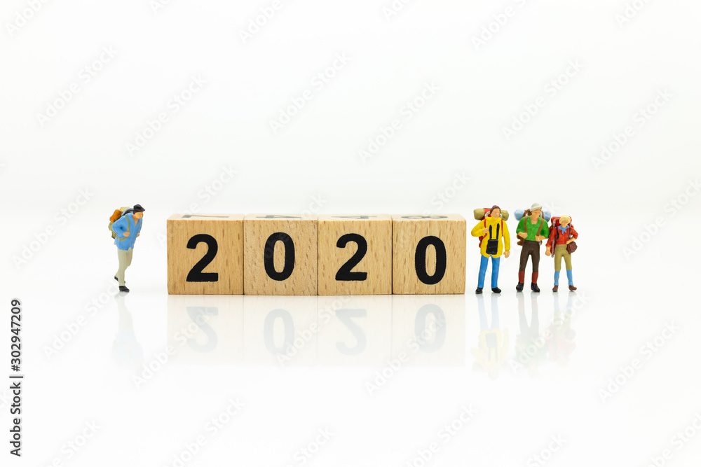 Miniature people, group travelers standing on wooden block 2020, new year. Image use for travel business concept.