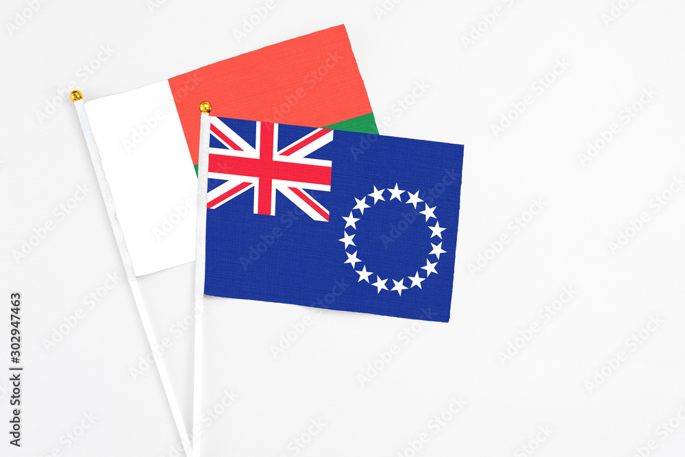 Fototapeta premium Cook Islands and Madagascar stick flags on white background. High quality fabric, miniature national flag. Peaceful global concept.White floor for copy space.