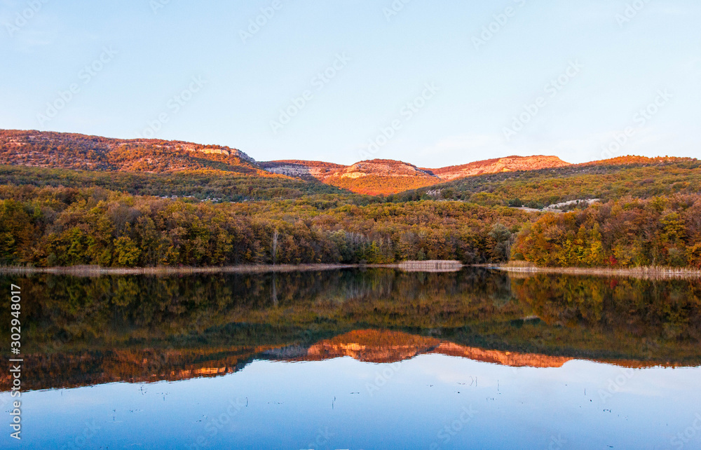 Autumn landscape of the lake at sunset. Lake and autumn forest in the mountains.