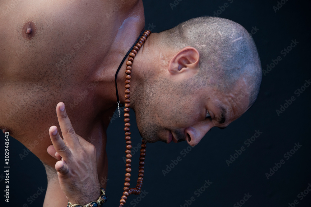 Fototapeta premium Fit hispanic man practicing yoga asana in a black studio.
