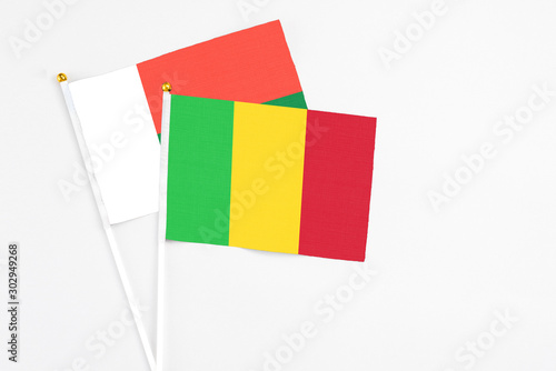 Mali and Madagascar stick flags on white background. High quality fabric, miniature national flag. Peaceful global concept.White floor for copy space.