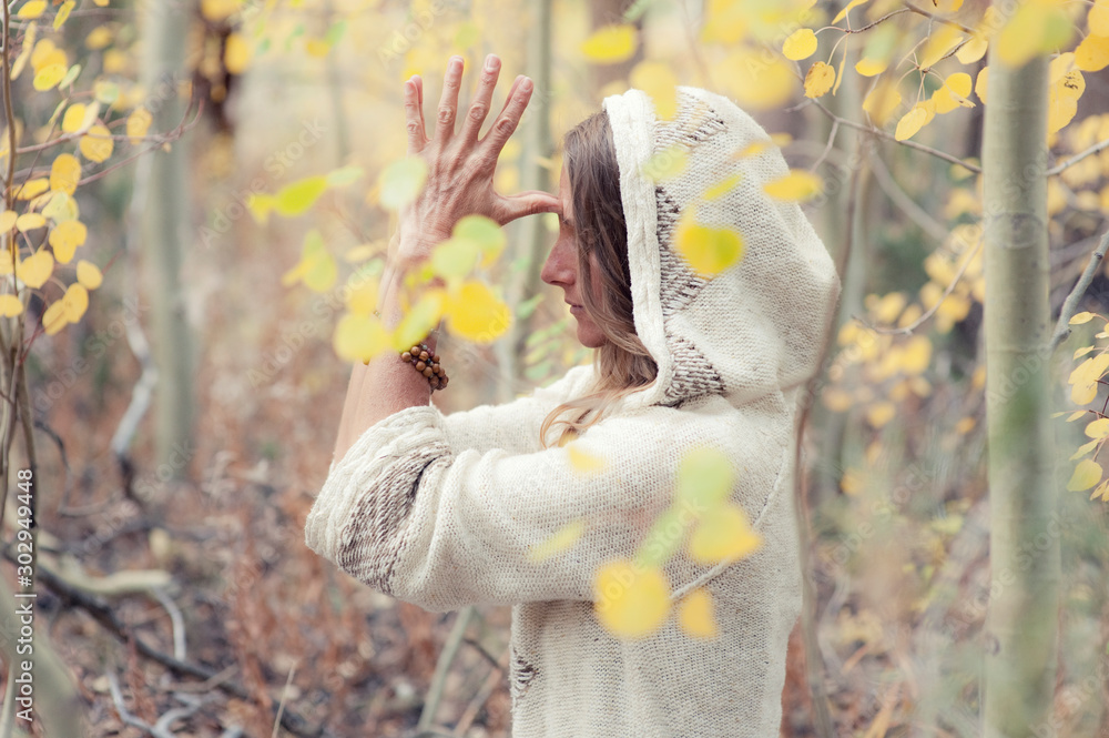 Φωτογραφία Grateful caucasian woman honoring her life outdoors in fall leaves with her hands to the forehead in a dynamic third eye namaste gesture wearing a sweater hoodie