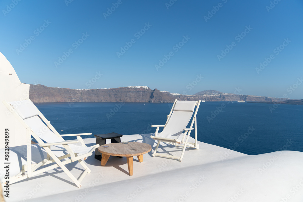 Two white deck chairs on rooftop deck overlooking Mediterranean