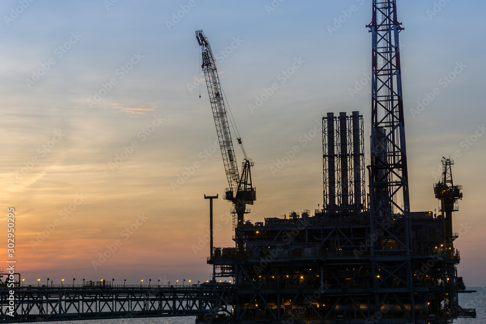 Silhouette of oil production platform during sunset