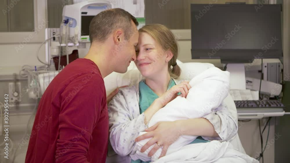 Medium shot of new parents fawning over their newborn baby in the hospital. Medium shot of new parents fawning over their newborn baby in the hospital.