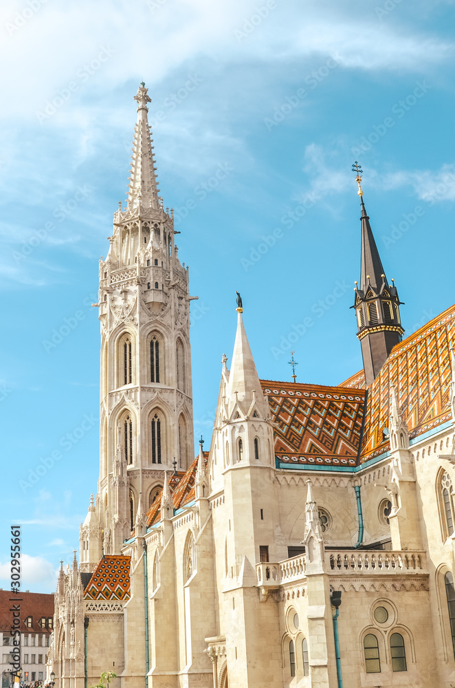 Fototapeta premium Vertical photo of the Matthias Church, also known as the Church of the Assumption of the Buda Castle, in Budapest, Hungary. Amazing Gothic Cathedral in the Hungarian capital city. Tourist landmark