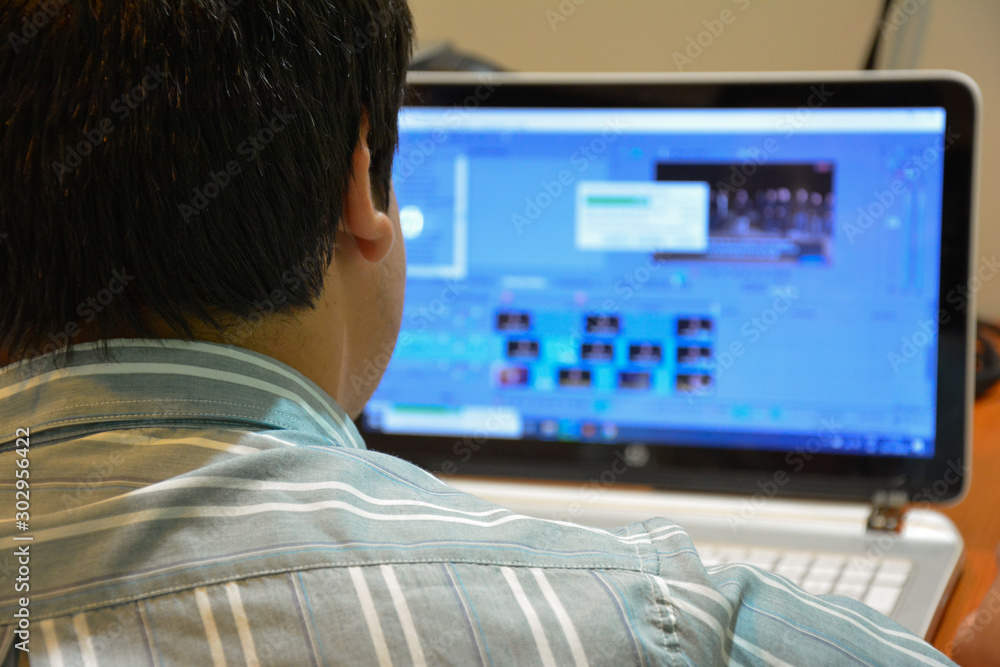  A man from working on the computer editing a video.