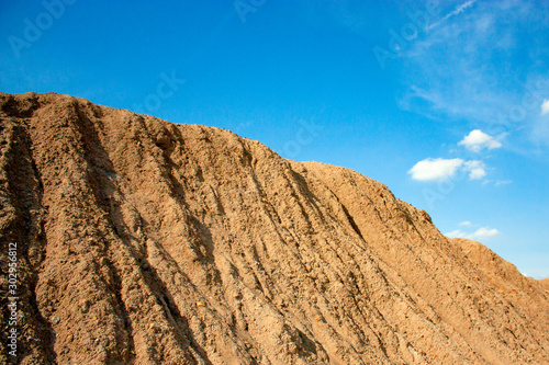 Mountainside with ravines from the rain. Blue sky and sand-colored mountainside.