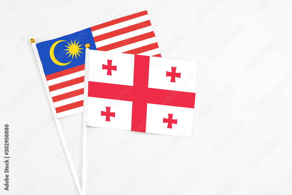Georgia and Malaysia stick flags on white background. High quality fabric, miniature national flag. Peaceful global concept.White floor for copy space.