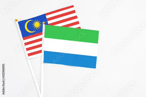 Sierra Leone and Malaysia stick flags on white background. High quality fabric, miniature national flag. Peaceful global concept.White floor for copy space.