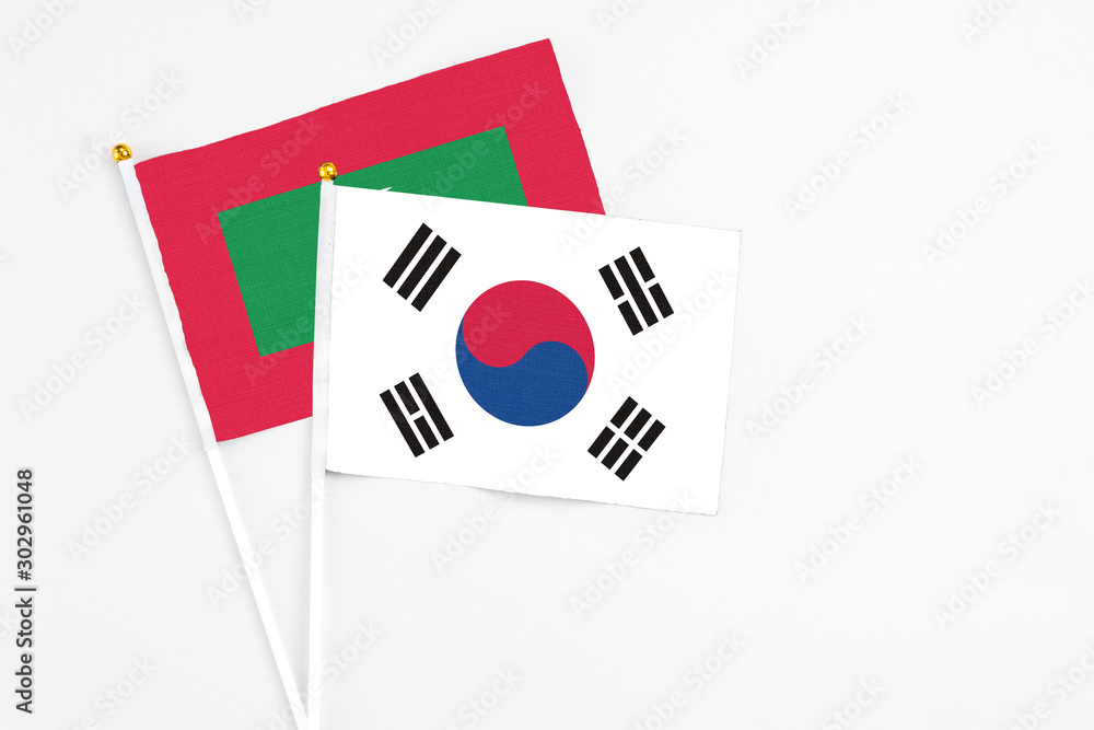South Korea and Maldives stick flags on white background. High quality fabric, miniature national flag. Peaceful global concept.White floor for copy space.