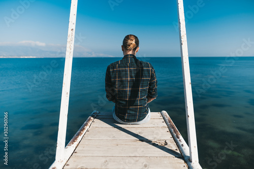 Man is sitting on the pier looking at the lake photo