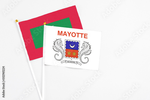 Mayotte and Maldives stick flags on white background. High quality fabric, miniature national flag. Peaceful global concept.White floor for copy space.