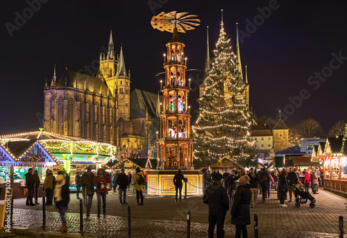Erfurt, Germany. Christmas pyramid at Christmas market on Domplatz (Cathedral Square) in night. St Mary's Cathedral is visible in the background. Church of St Severus is hidden by the Christmas tree.