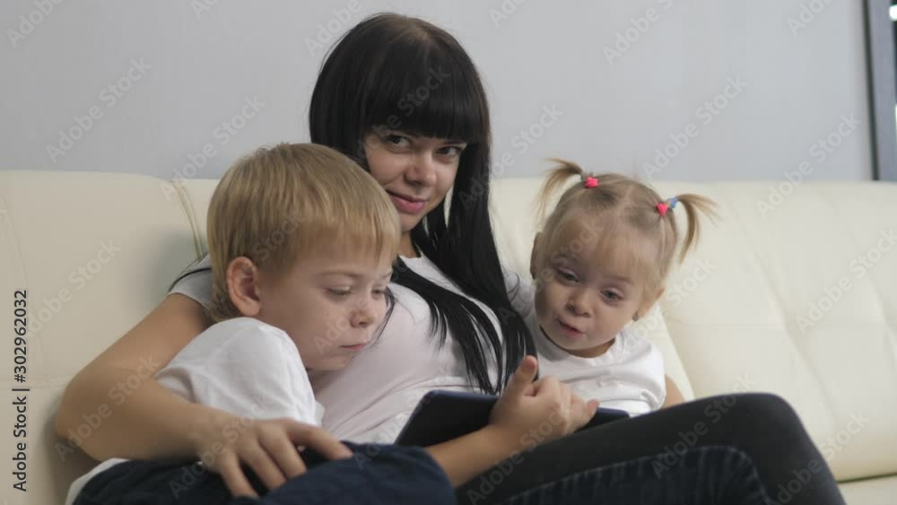 happy family a with digital tablet teamwork leisure concept. mom and children watch an online movie series on a digital tablet. mother and little boy and girl watch cartoons on a digital tablet happy family a with digital tablet teamwork leisure concept. mom and children watch an online movie series on a digital tablet. mother and little boy and girl watch cartoons on a digital tablet