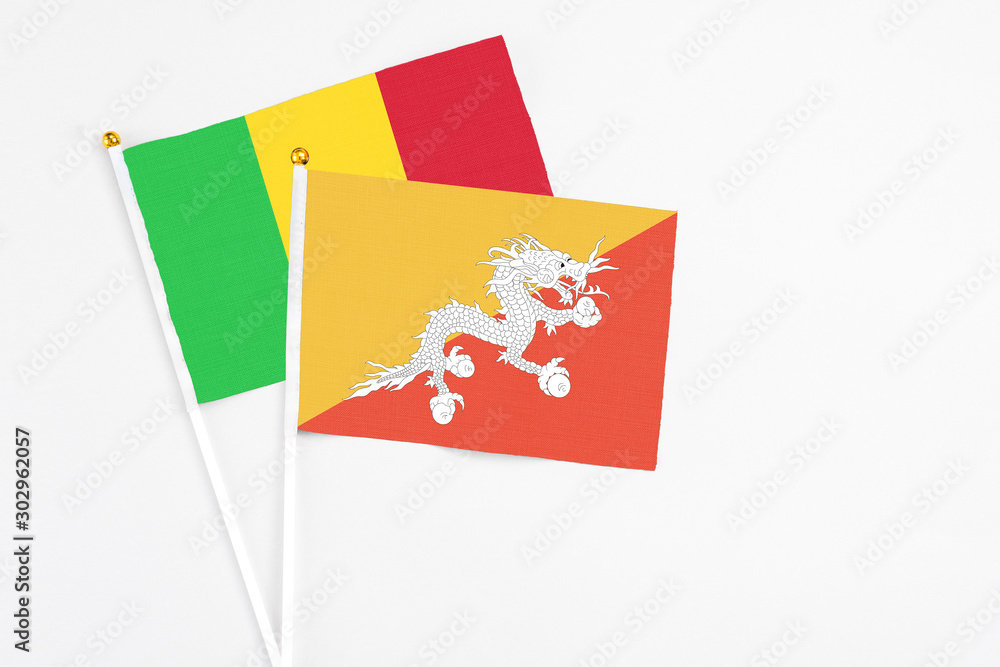 Bhutan and Mali stick flags on white background. High quality fabric, miniature national flag. Peaceful global concept.White floor for copy space. Bhutan and Mali stick flags on white background. High quality fabric, miniature national flag. Peaceful global concept.White floor for copy space.