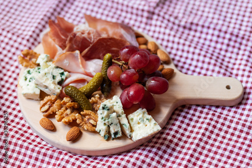 Delicious aperetif for evening home party: wooden borad with french blue cheese, bacon, walnut and almond, italian sweet grapes. Closeup, top view photo