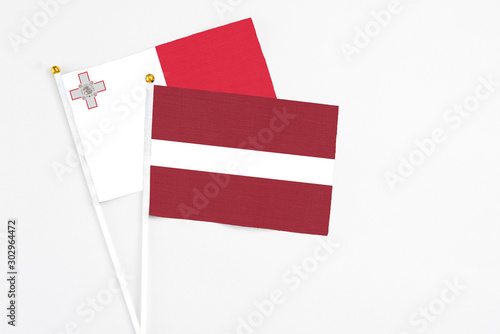 Latvia and Malta stick flags on white background. High quality fabric, miniature national flag. Peaceful global concept.White floor for copy space.