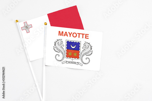 Mayotte and Malta stick flags on white background. High quality fabric, miniature national flag. Peaceful global concept.White floor for copy space.