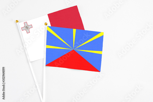 Reunion and Malta stick flags on white background. High quality fabric, miniature national flag. Peaceful global concept.White floor for copy space.