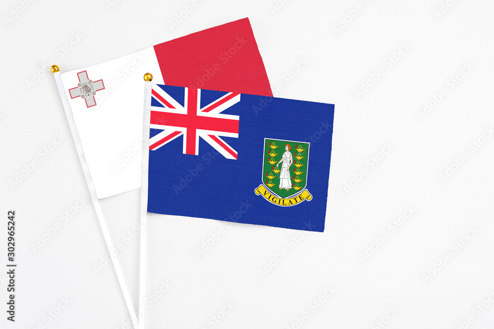 Fototapeta premium British Virgin Islands and Malta stick flags on white background. High quality fabric, miniature national flag. Peaceful global concept.White floor for copy space.