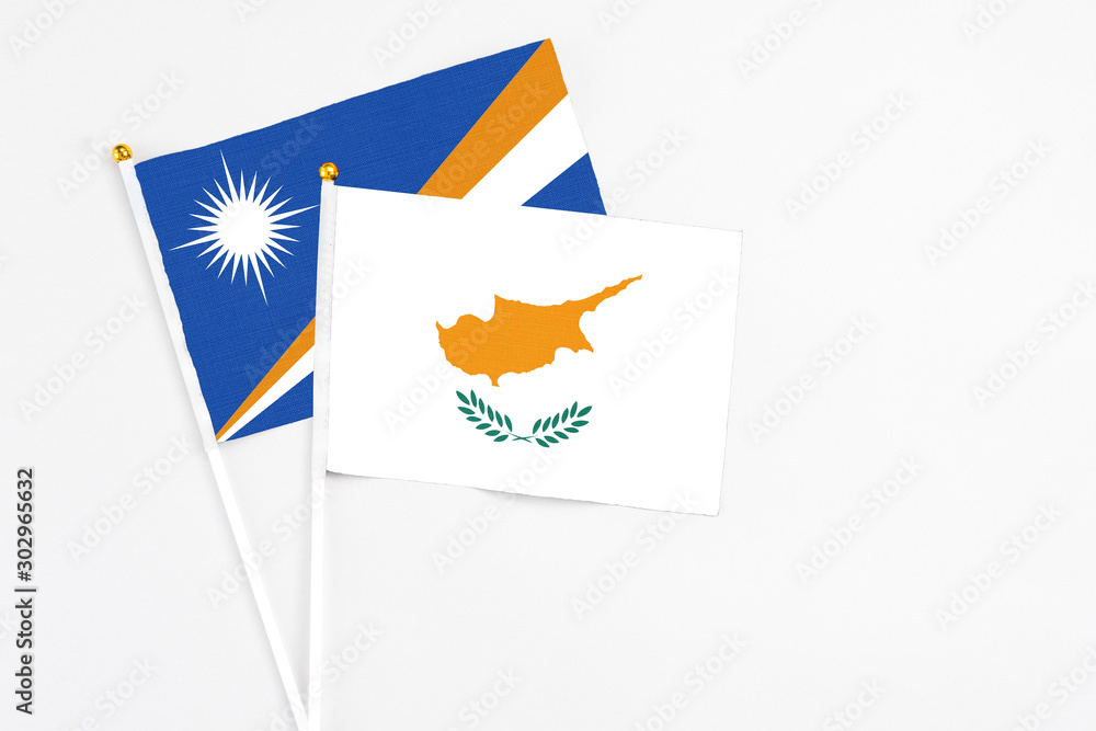 Obraz premium Cyprus and Marshall Islands stick flags on white background. High quality fabric, miniature national flag. Peaceful global concept.White floor for copy space.