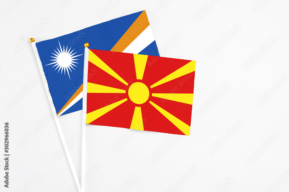 Macedonia and Marshall Islands stick flags on white background. High quality fabric, miniature national flag. Peaceful global concept.White floor for copy space.