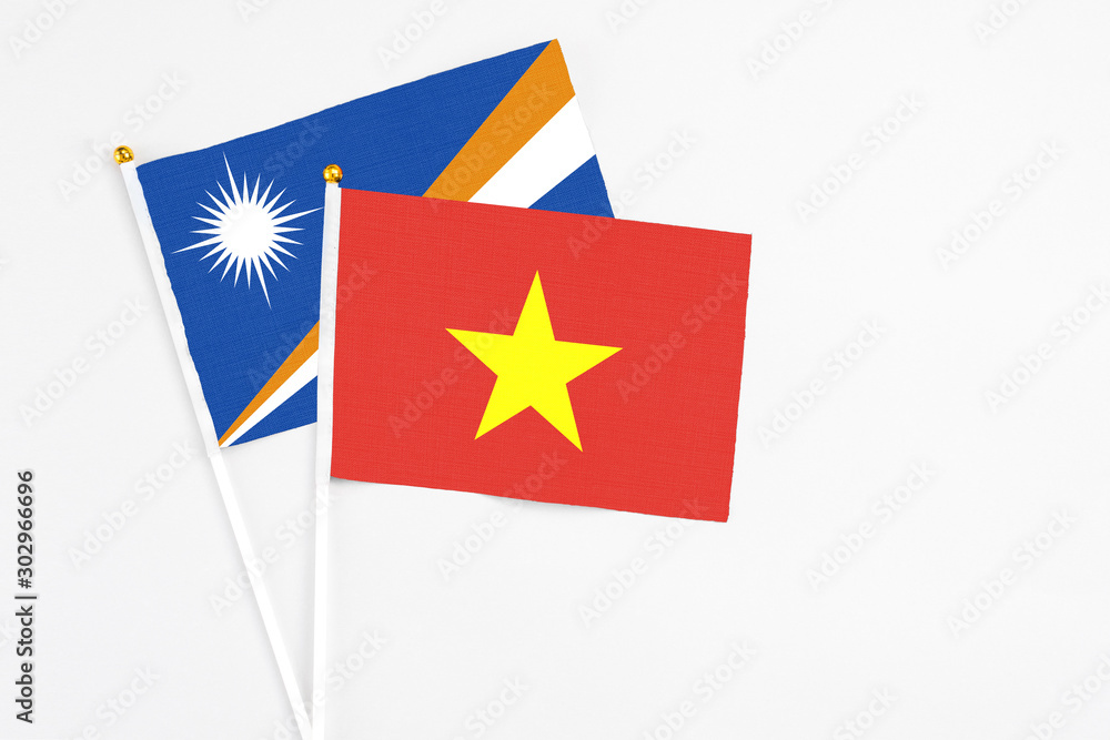 Vietnam and Marshall Islands stick flags on white background. High quality fabric, miniature national flag. Peaceful global concept.White floor for copy space. Vietnam and Marshall Islands stick flags on white background. High quality fabric, miniature national flag. Peaceful global concept.White floor for copy space.
