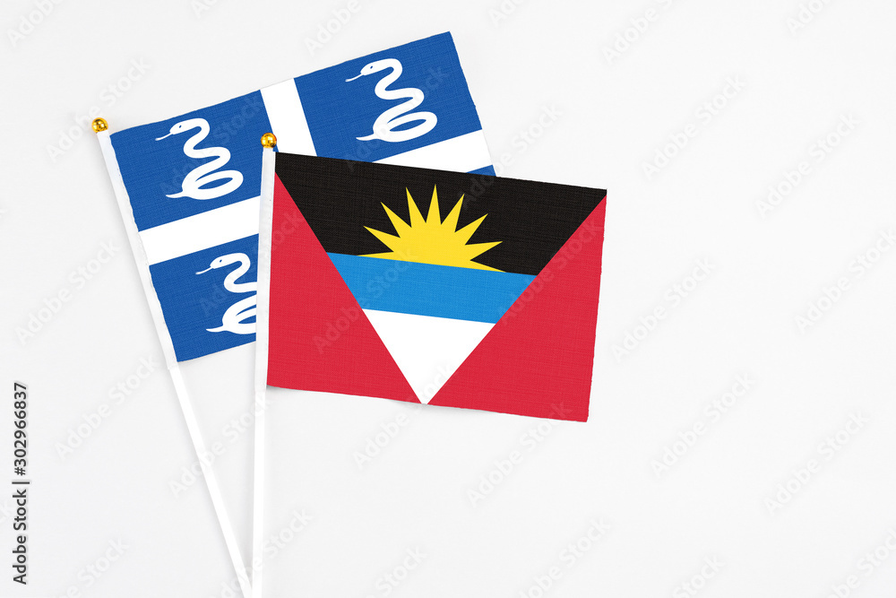 Obraz premium Antigua and Barbuda and Martinique stick flags on white background. High quality fabric, miniature national flag. Peaceful global concept.White floor for copy space.