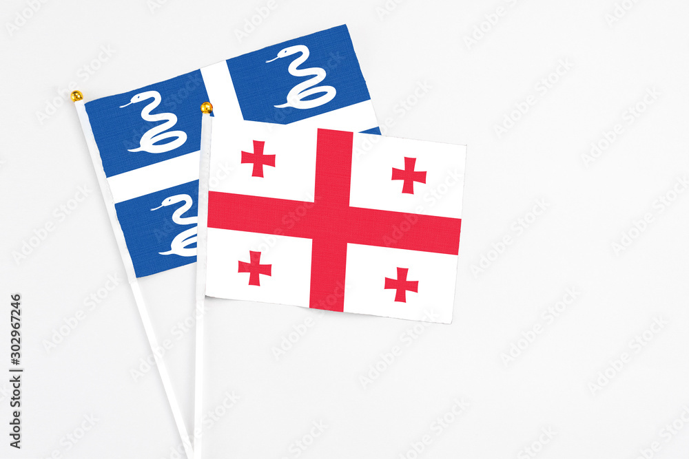 Georgia and Martinique stick flags on white background. High quality fabric, miniature national flag. Peaceful global concept.White floor for copy space.