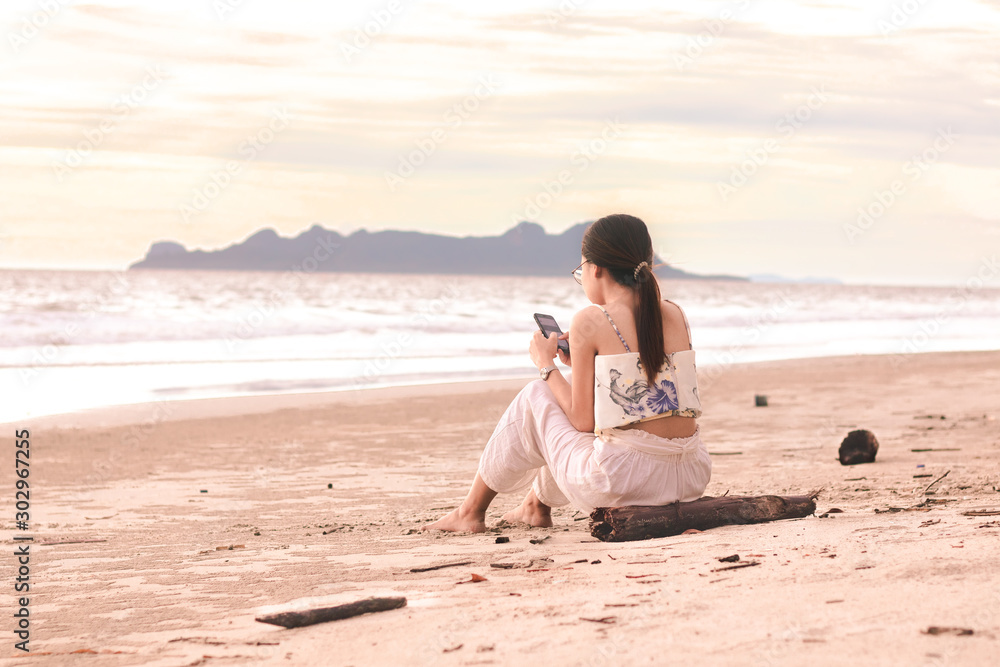 Young woman using mobile phone on the beach