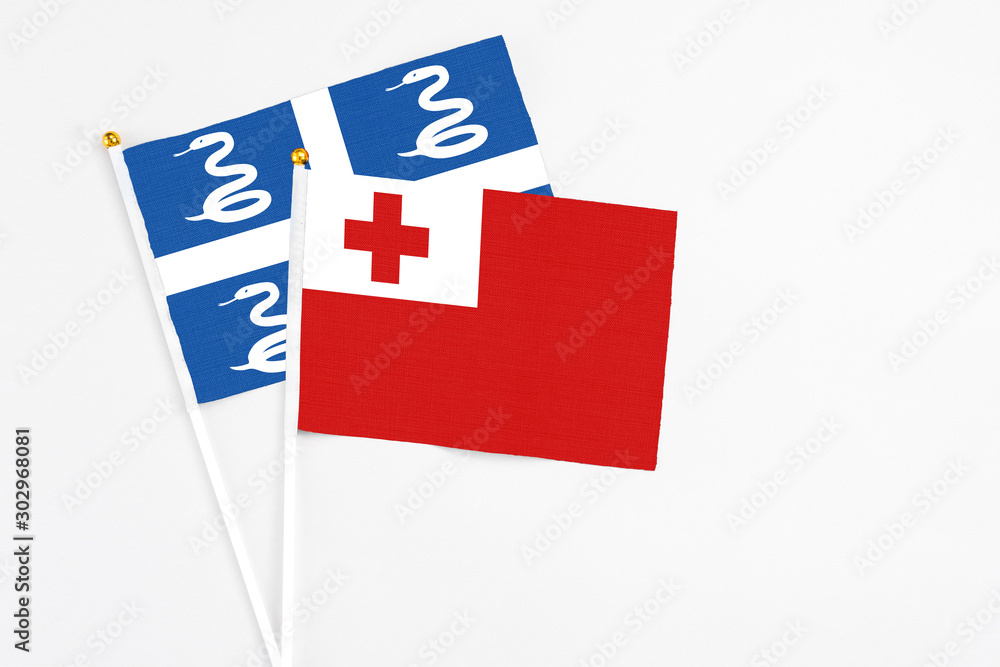 Tonga and Martinique stick flags on white background. High quality fabric, miniature national flag. Peaceful global concept.White floor for copy space.
