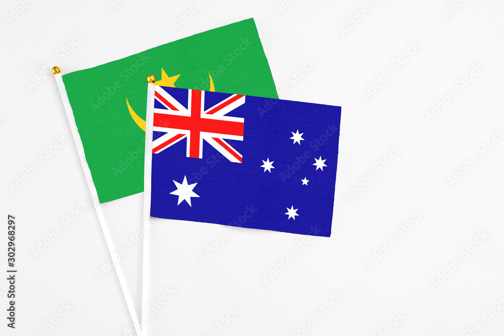 Fototapeta premium Australia and Mauritania stick flags on white background. High quality fabric, miniature national flag. Peaceful global concept.White floor for copy space.