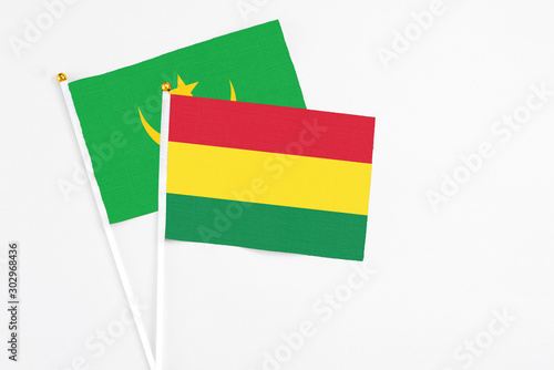 Bolivia and Mauritania stick flags on white background. High quality fabric, miniature national flag. Peaceful global concept.White floor for copy space.