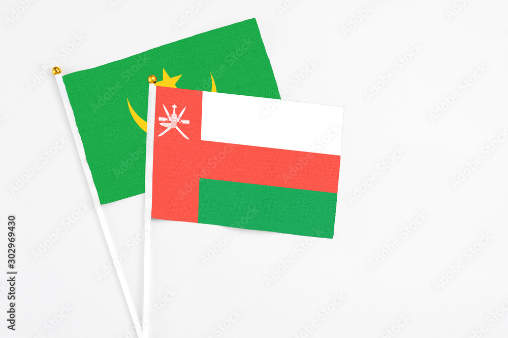 Oman and Mauritania stick flags on white background. High quality fabric, miniature national flag. Peaceful global concept.White floor for copy space.