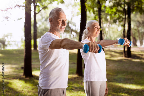 Delighted man and woman lifting weights stock photo