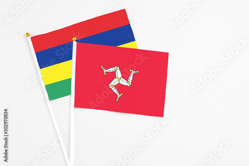 Isle Of Man and Mauritius stick flags on white background. High quality fabric, miniature national flag. Peaceful global concept.White floor for copy space.
