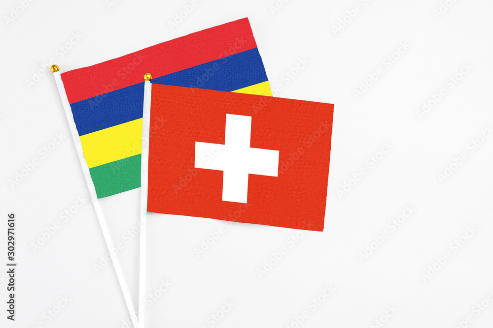 Switzerland and Mauritius stick flags on white background. High quality fabric, miniature national flag. Peaceful global concept.White floor for copy space.